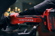 Photo of Craftsman cordless angle grinder, SKU CMCG451B, red and black design, gloved hand holding tool in use.