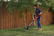 Photo of CRAFTSMAN CMCK197M1 cordless string trimmer used outdoors near trees and a wooden fence.