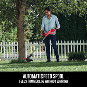 Photo of person using Craftsman string trimmer CMCST915B in a yard with trees and white picket fence.