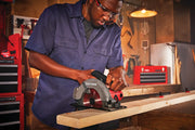 Photo of a person using a Craftsman CMES500 circular saw to cut a wooden board in a workshop setting.