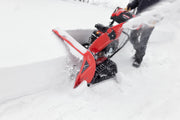 Photo of Craftsman CMGB223104 snow blower clearing deep snow, side angle view with red body and tracked wheels.