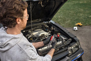 A person wearing safety glasses and gloves holds a set of CRAFTSMAN hex keys while working on a car engine with the hood