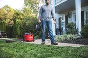 Photo of a person using a red Craftsman wet/dry vacuum, SKU CMXEVBE17607, on a walkway outside a house.