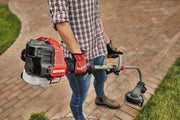 Photo of a person using a Craftsman string trimmer CMXGTAMDCS25 on a brick pathway near grass.