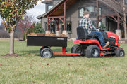 Photo of Craftsman lawn tractor towing CMXGZBF7124355 black utility cart loaded with mulch on grass.