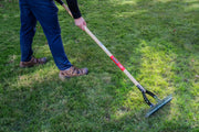 Photo of a person using a Craftsman lawn rake, SKU CMXMLTP35317, with wood handle on grass outdoors.
